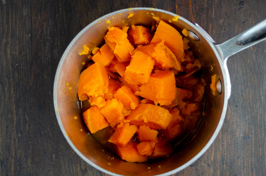Cubed sweet potatoes cooking in a stainless steel pot
