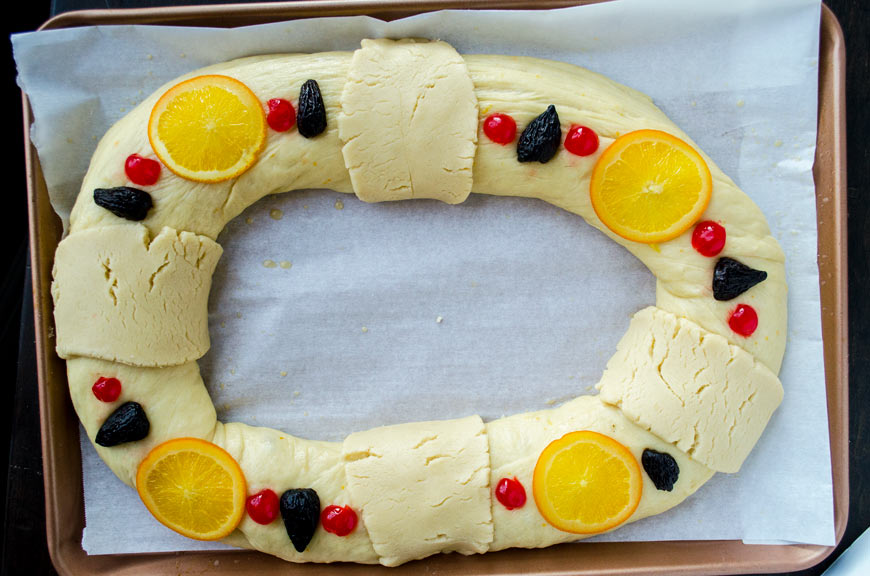 Risen vegan rosca de reyes dough with fruit decorations and sugar paste on it.