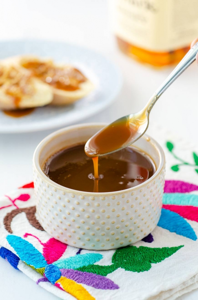 Vegan cajeta envinada in a small dish with a spoon dipping into it.