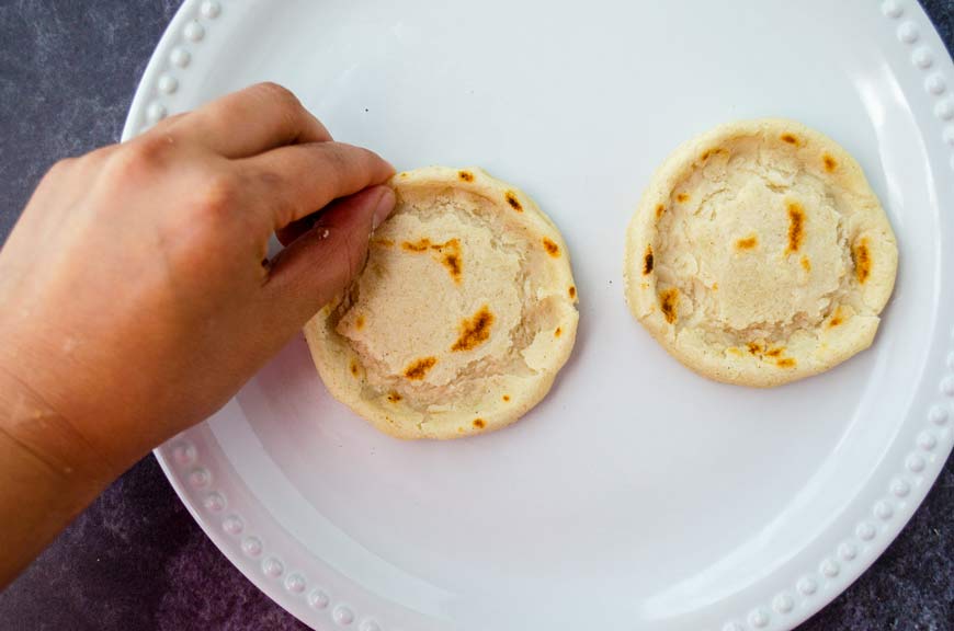 two sopes on a white plate and a a hand pinching the edhes