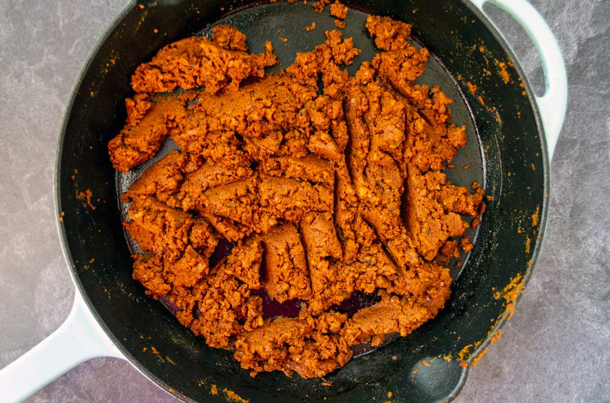 red colored walnut meat on a cast iron pan with teal handle