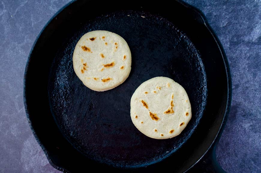 two sopes cooking on a cast iron pan with a black marble background