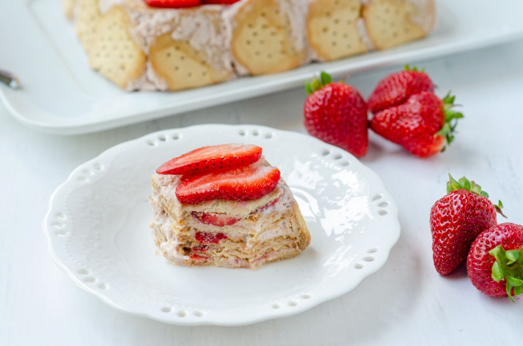 A slice of carlota de limon showing the different layers and topped with sliced strawberries on a white plate.