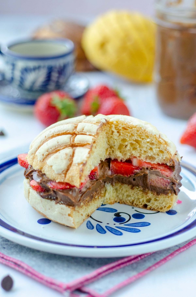 stuffed concha with vegan nutella and strawberries with a piece cut off to show the inside