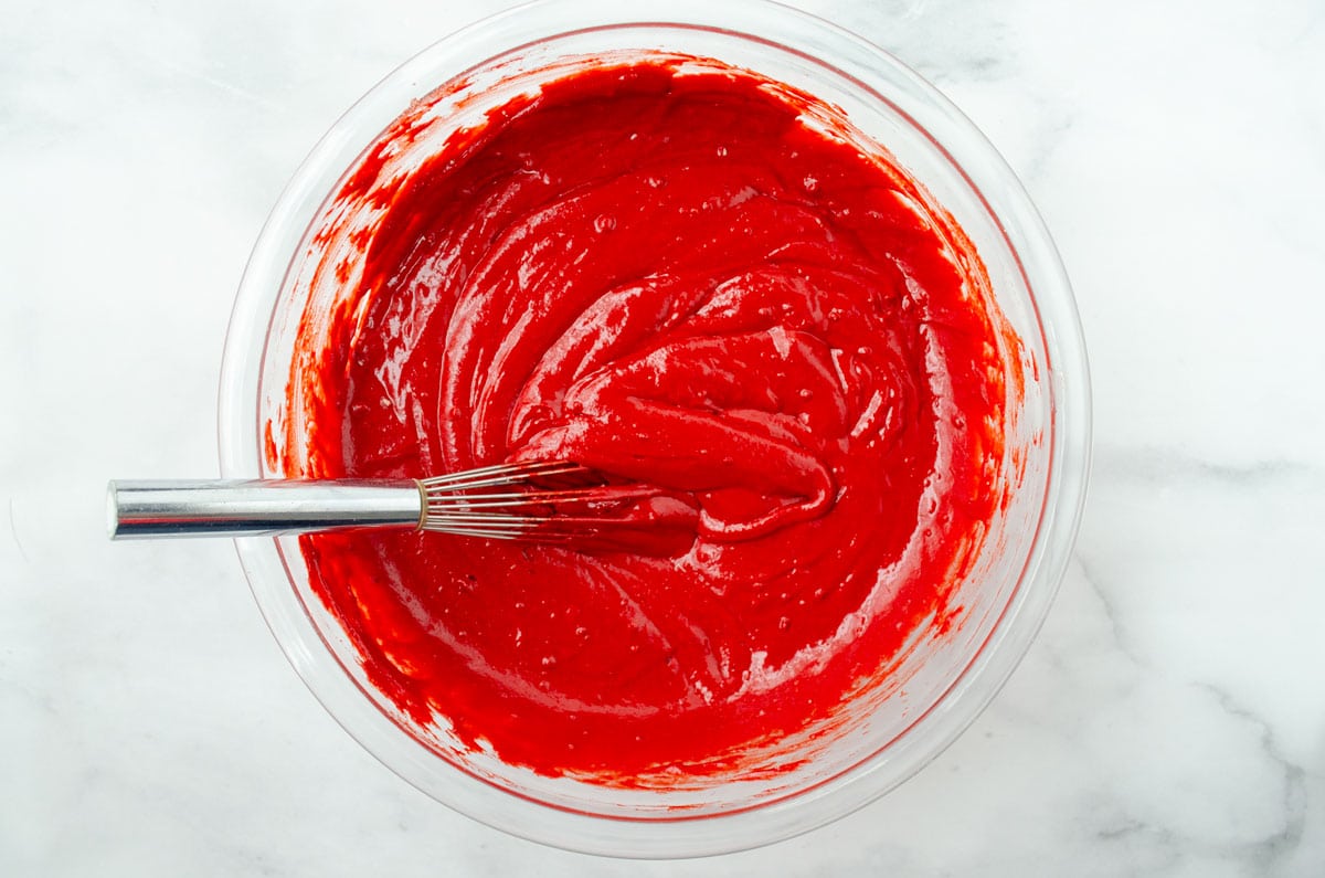 red cake batter in a glass bowl