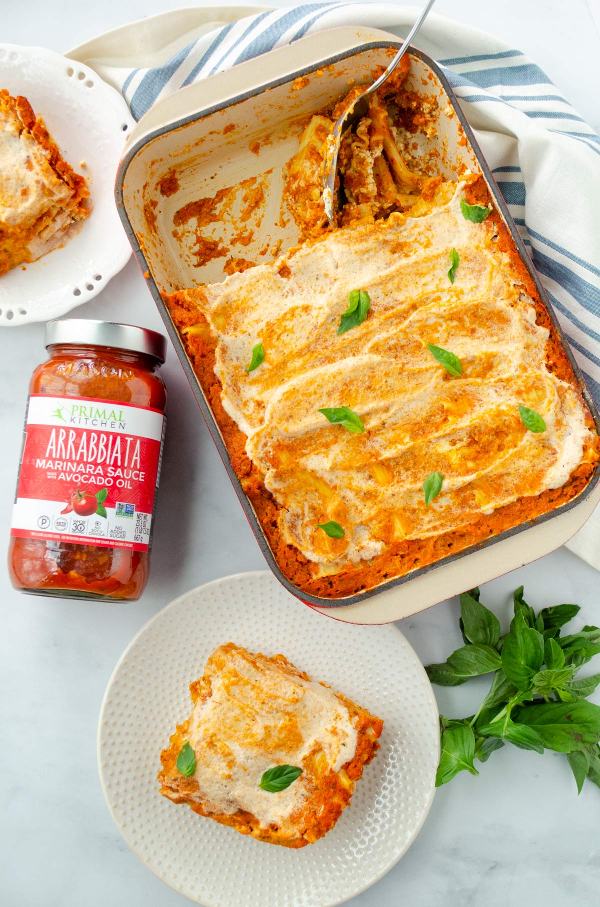 lasagna on a white blue towel, a piece of lasagna, jar of sauce