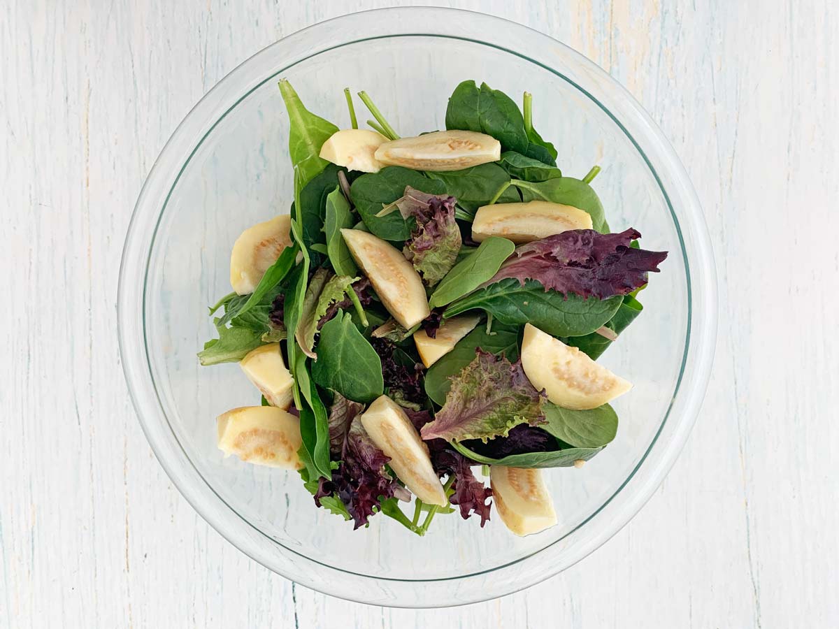 glass bowl with mixed greens and guava