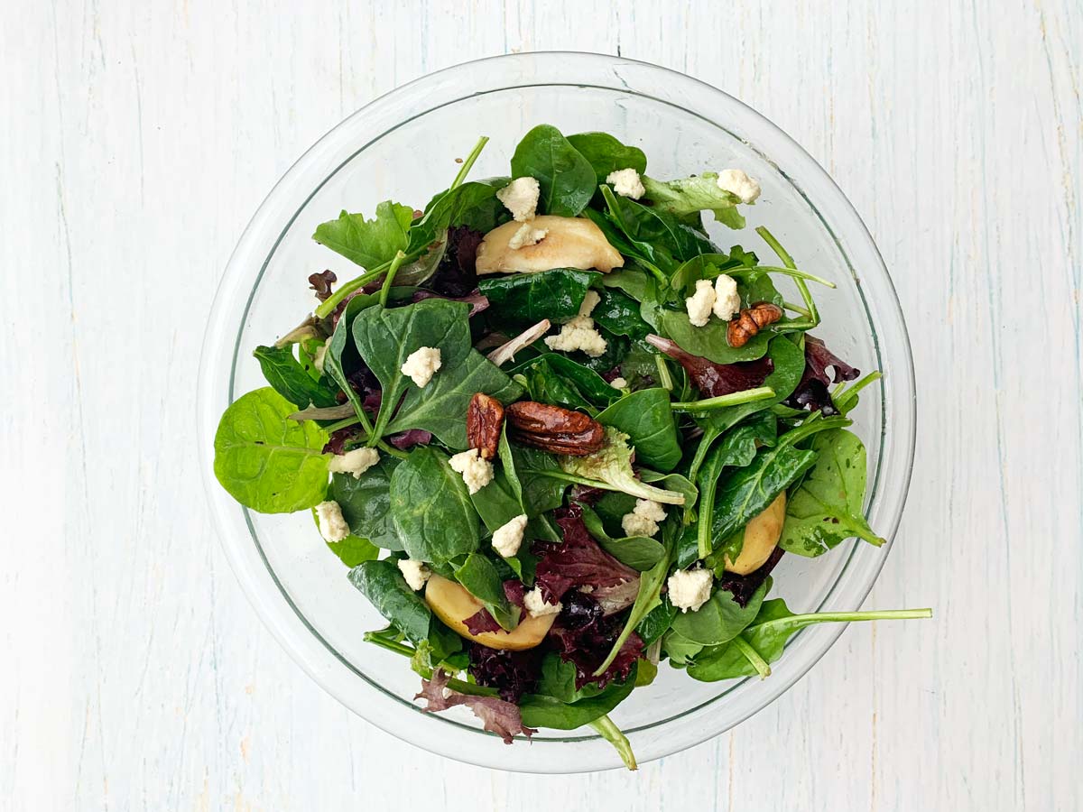 glass bowl with salad, queso fresco and candied pecans