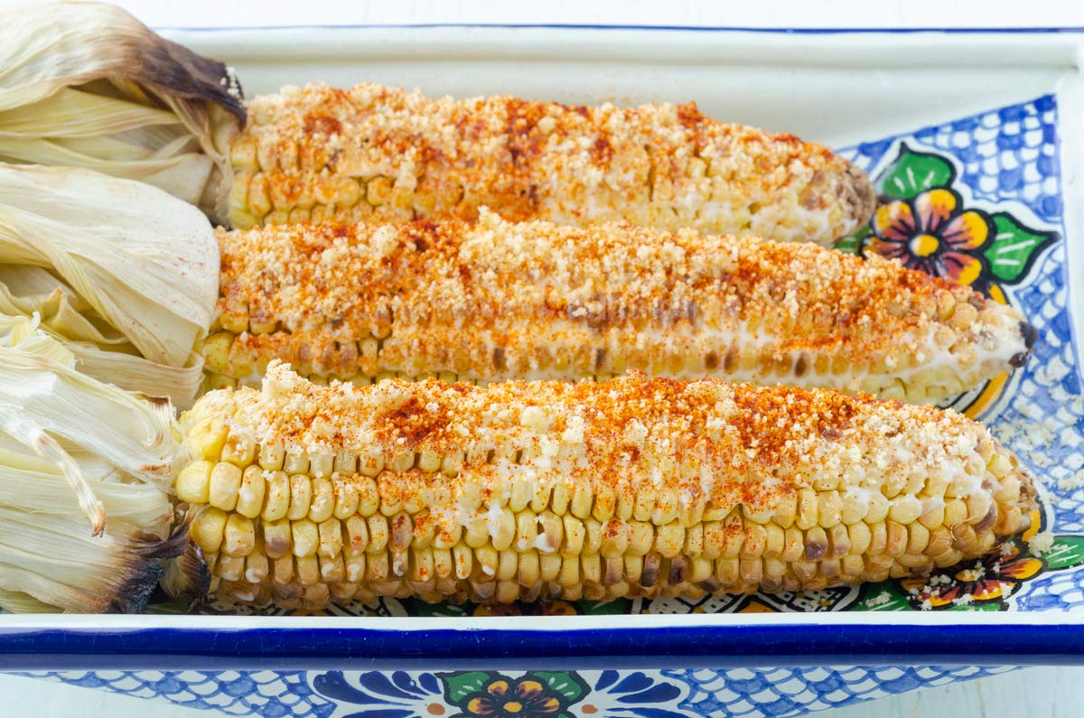 3 cobs of corn covered in mayo, chile powder, and cheese