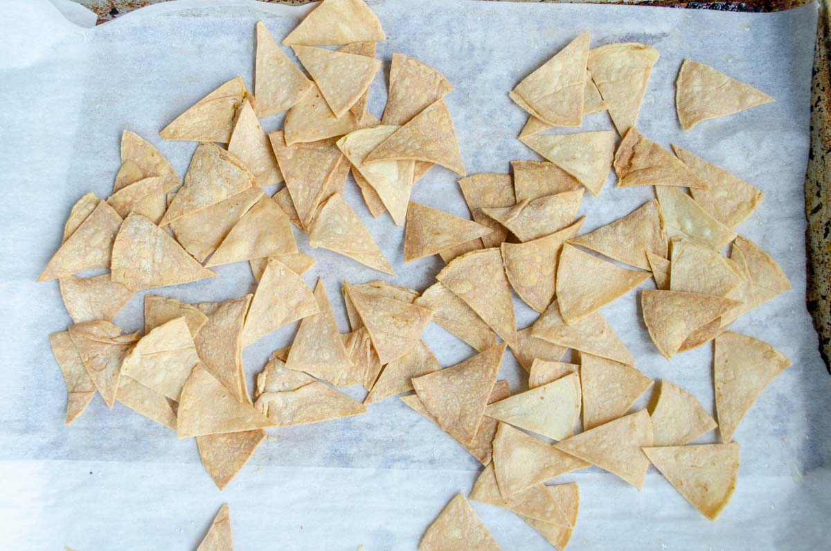 baked tortilla chips on a sheet tray lined with parchment