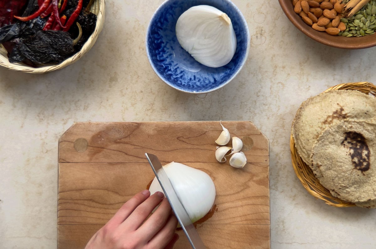 onion being cut on a small wooden board