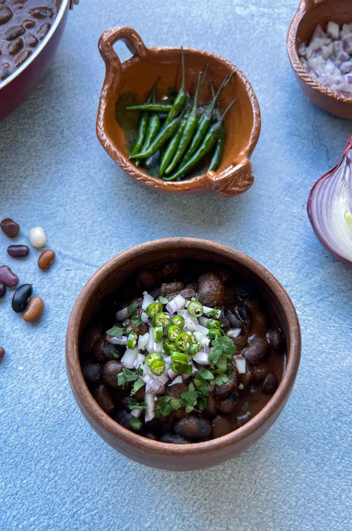 ayocotes in mole in a small clay bowl on a blue background