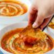 piece os sourdough toast dipping into tomato soup