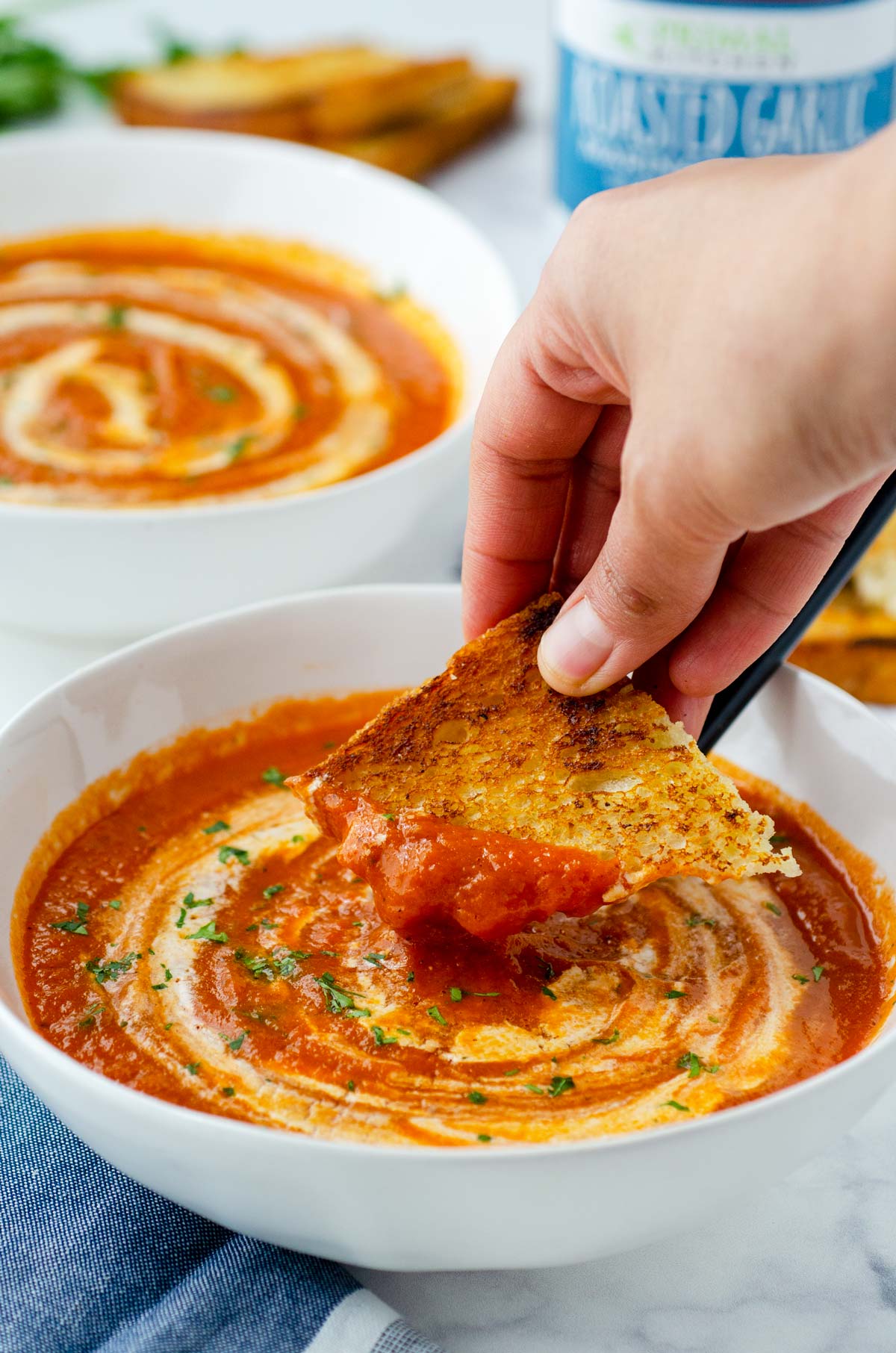 piece os sourdough toast dipping into tomato soup