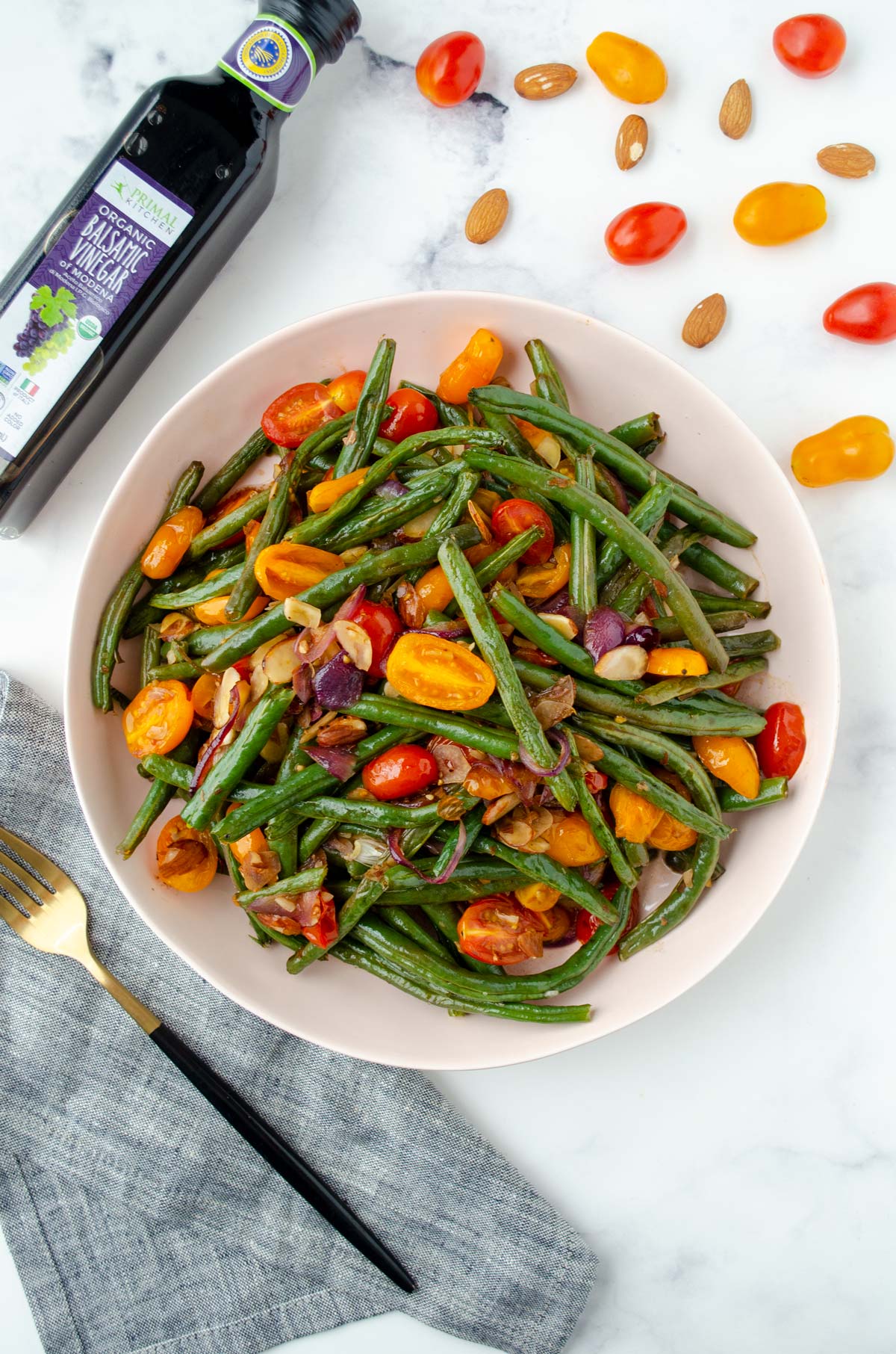 pink bowl of green beans with tomatoes and almonds