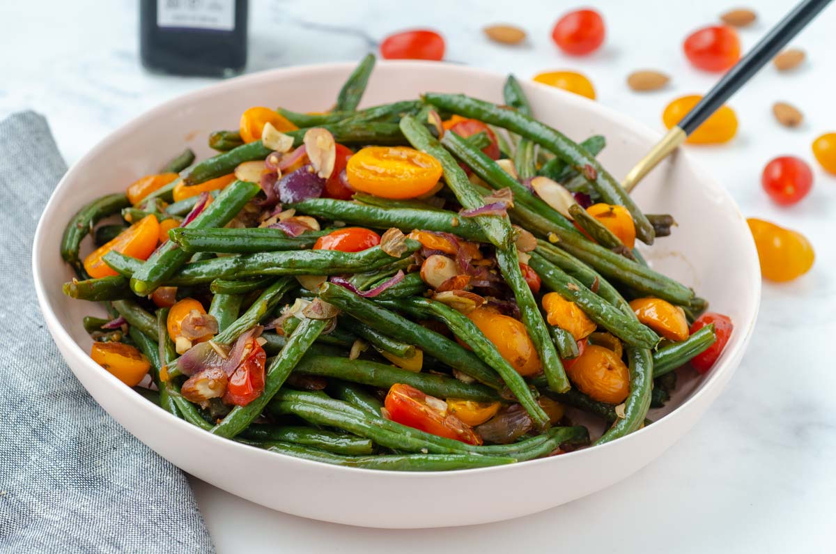 bowl of green beans with almonds, tomatoes and onion