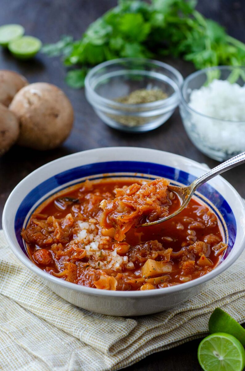 a bowl of vegan menudo with a lifted spoon