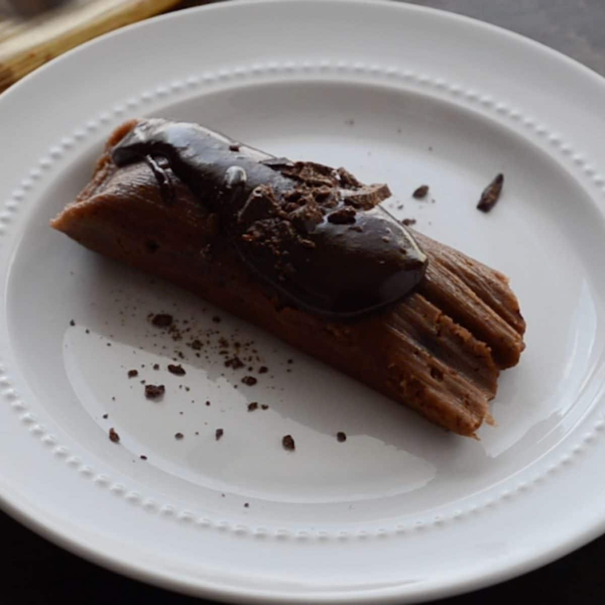 chocolate tamal topped with chocolate sauce and shaved chocolate