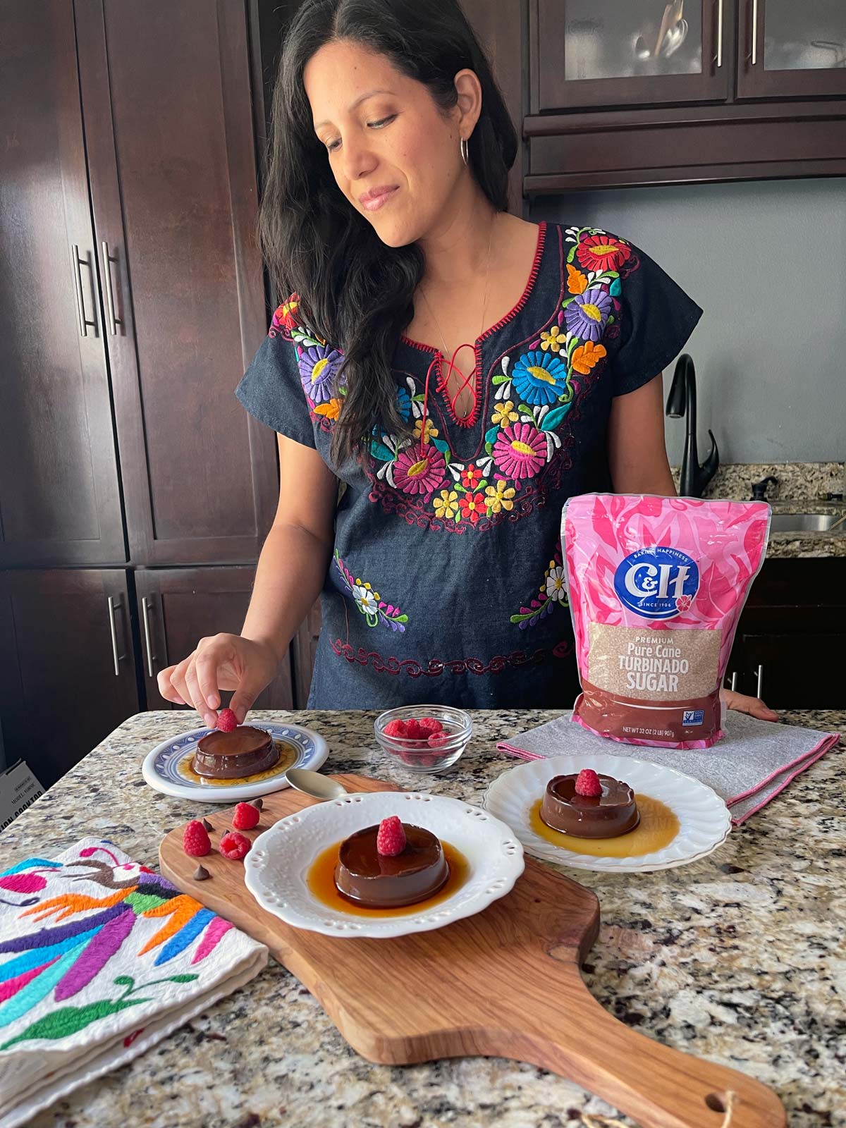 a woman placing a raspberry on a flan