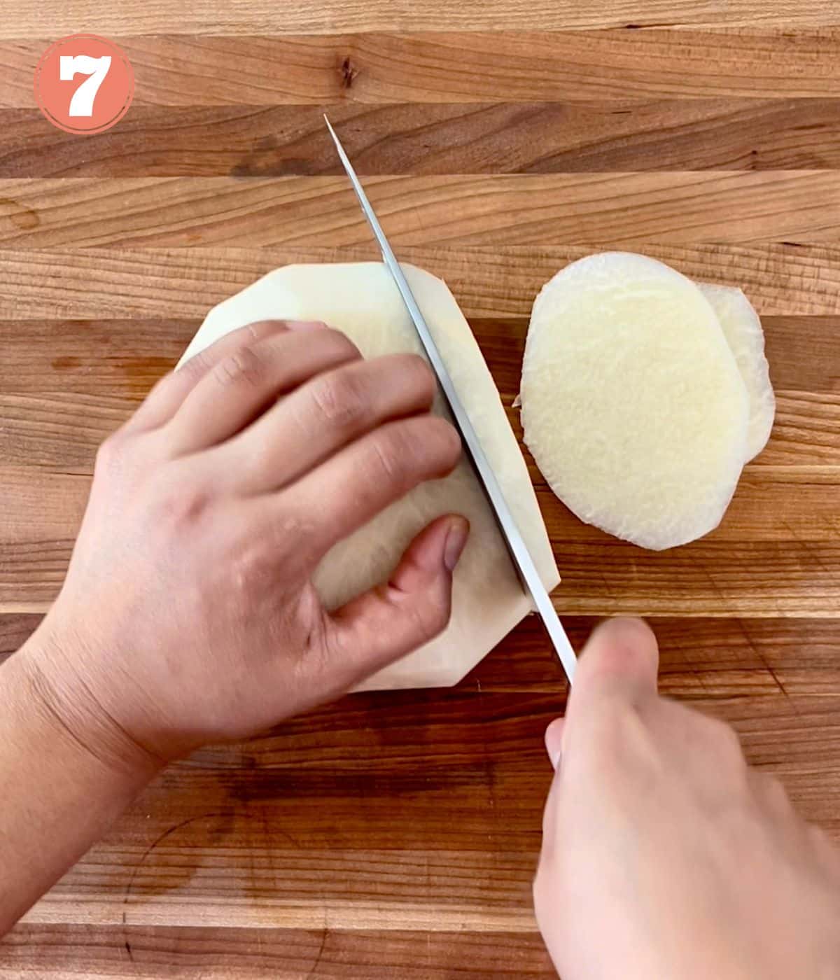 A knife cutting into a peeled jicama.