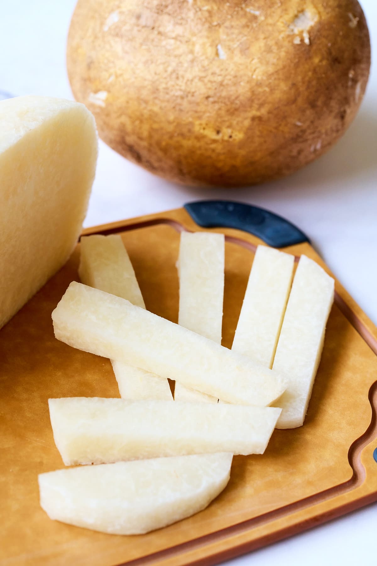 Jicama cut into batons on a wooden cutting board.