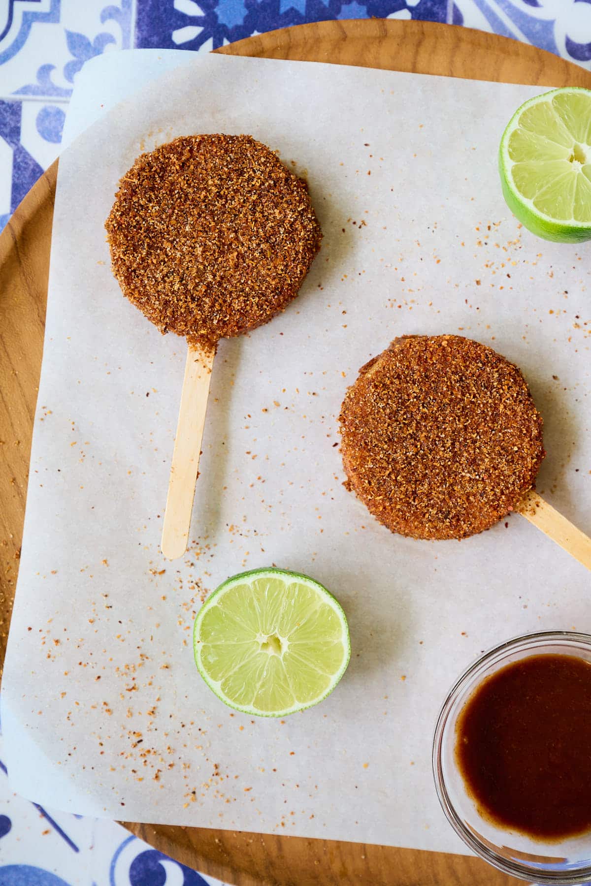Two jicaletas and two slices of lime on a wooden plate.