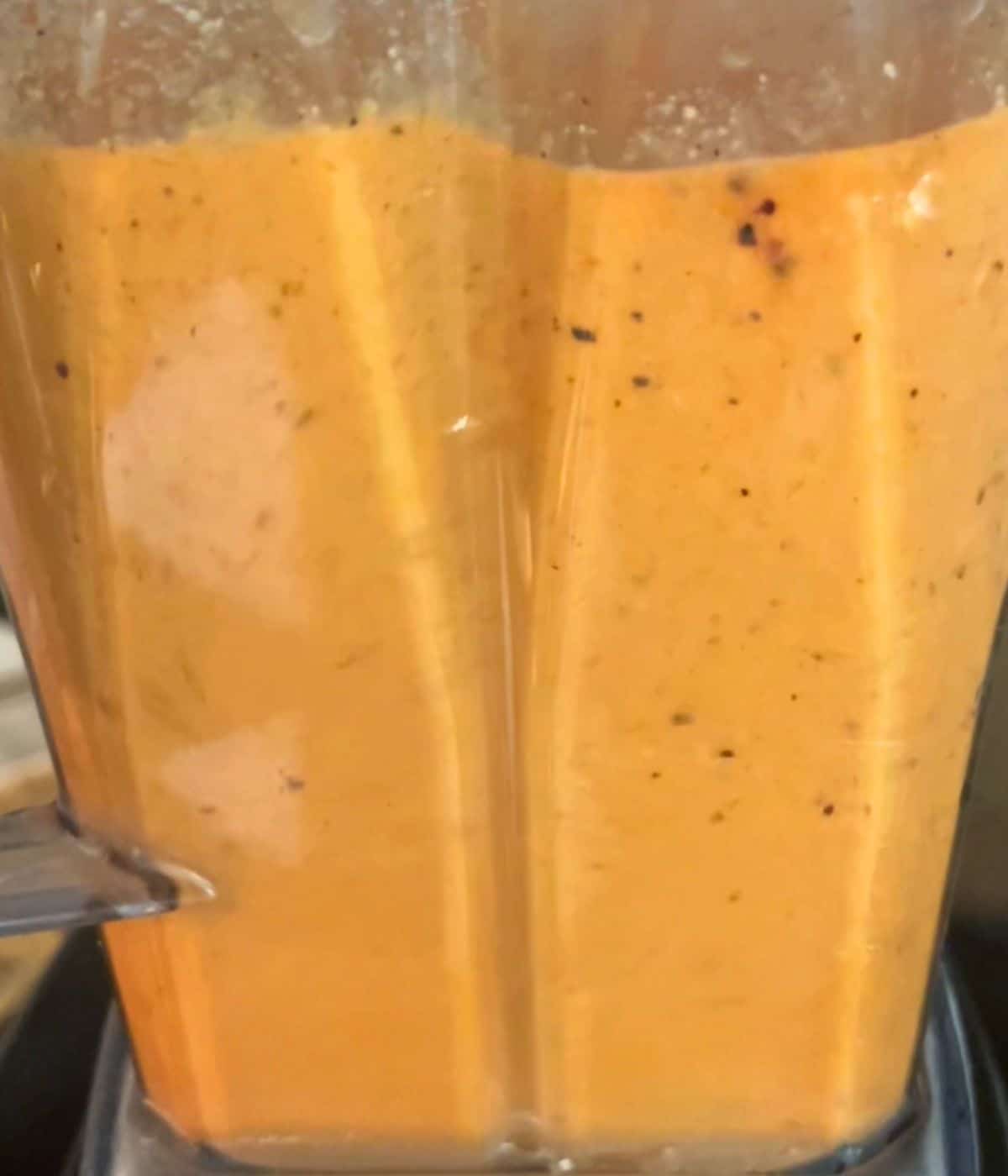 sauce being blended in tall plastic blender container
