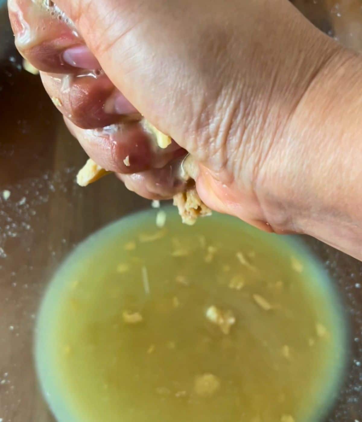 A hand squeezing soy curls over a bowl.