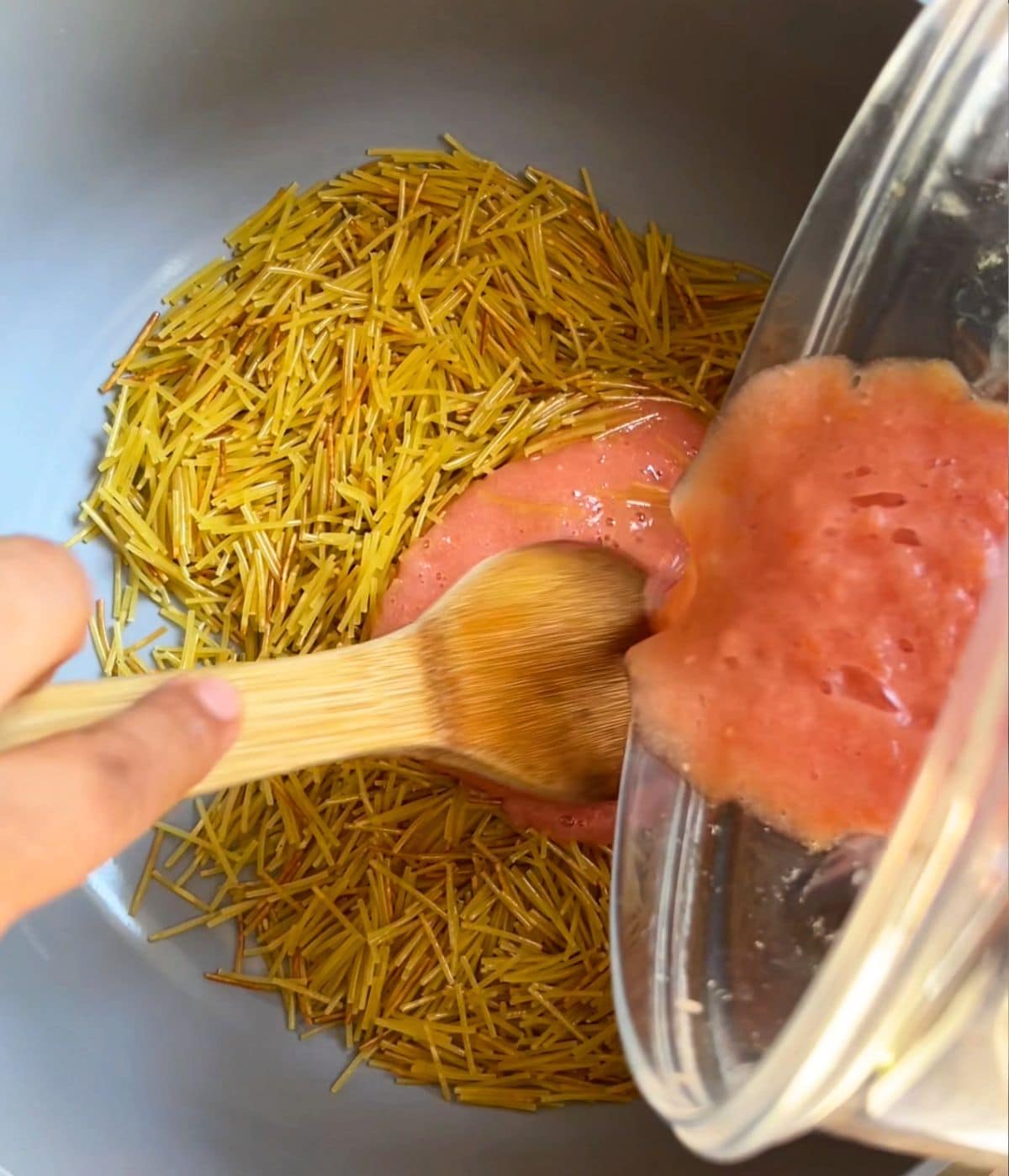 Tomato sauce being poured into noodles.