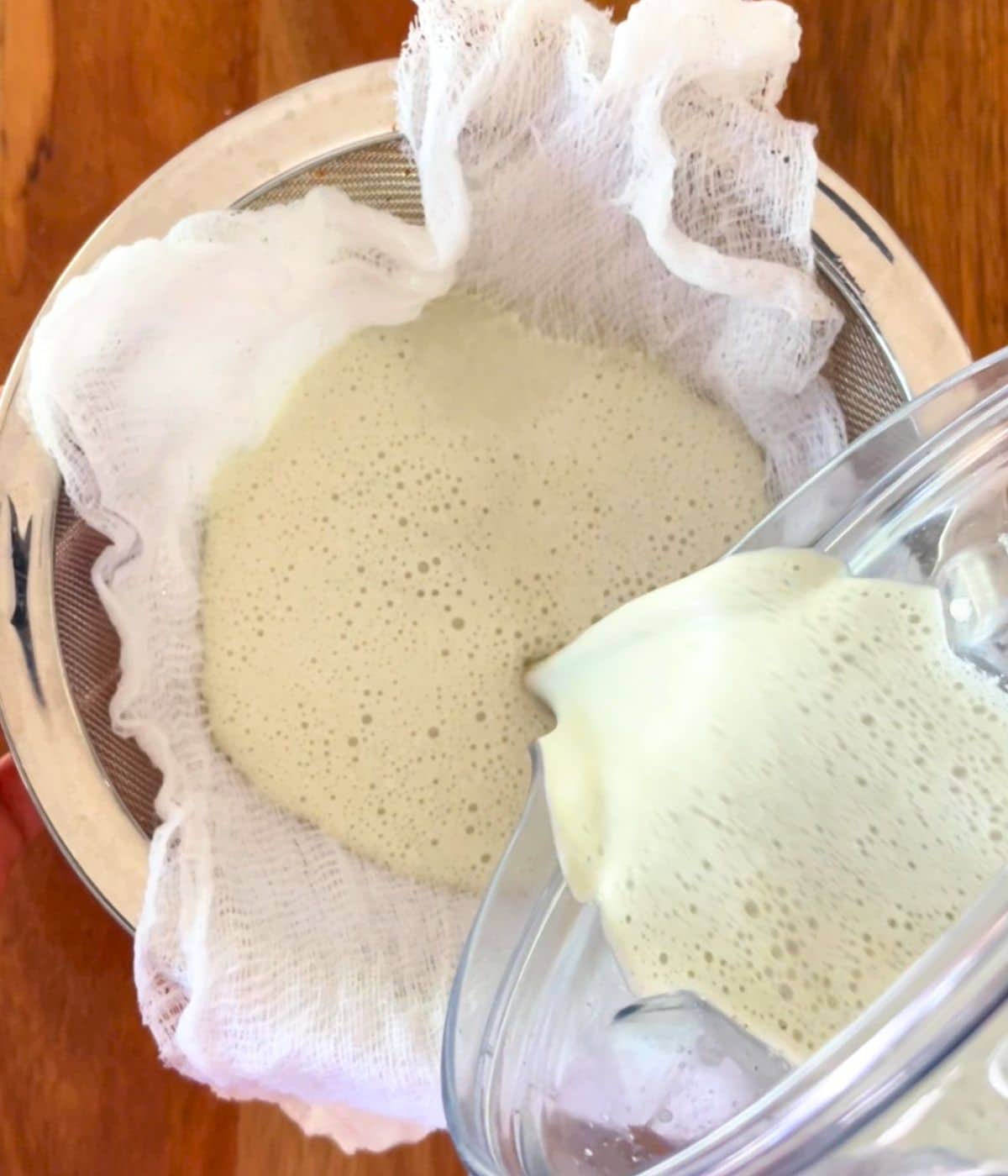Pumpkin seed milk being poured into a cheesecloth.