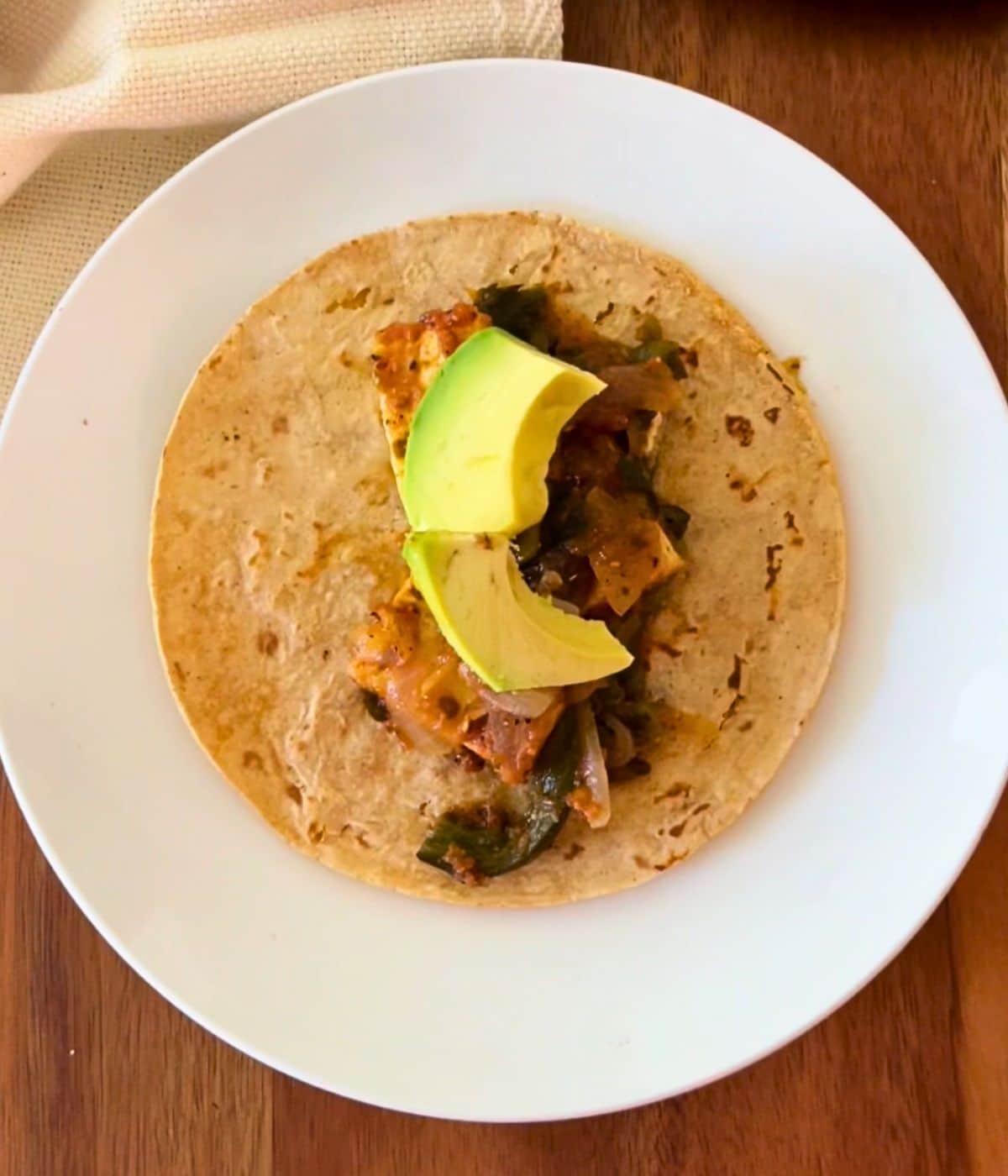 Rajas con queso on a tortillas with a slice of avocado.