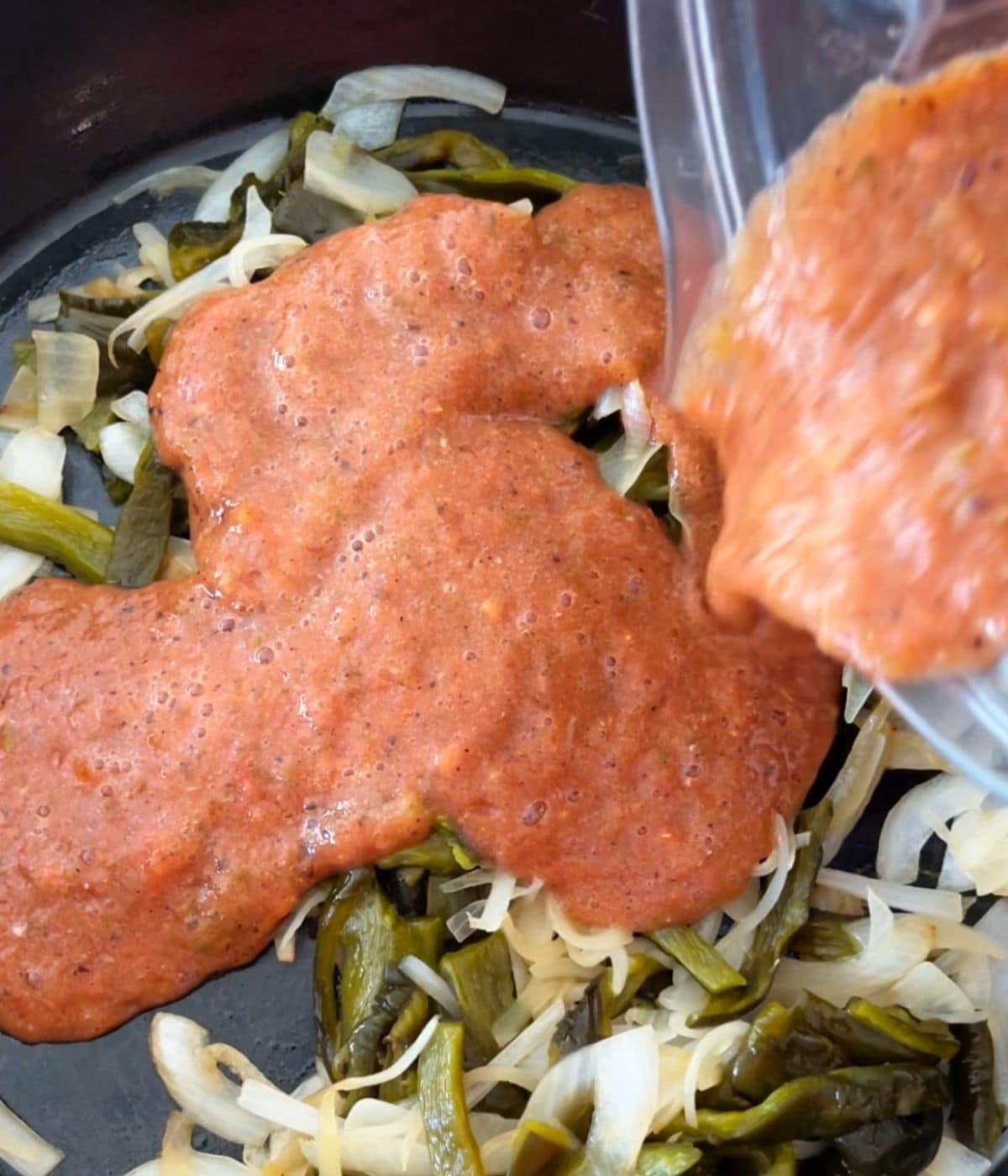 Salsa poured from the blender onto skillet with onions.