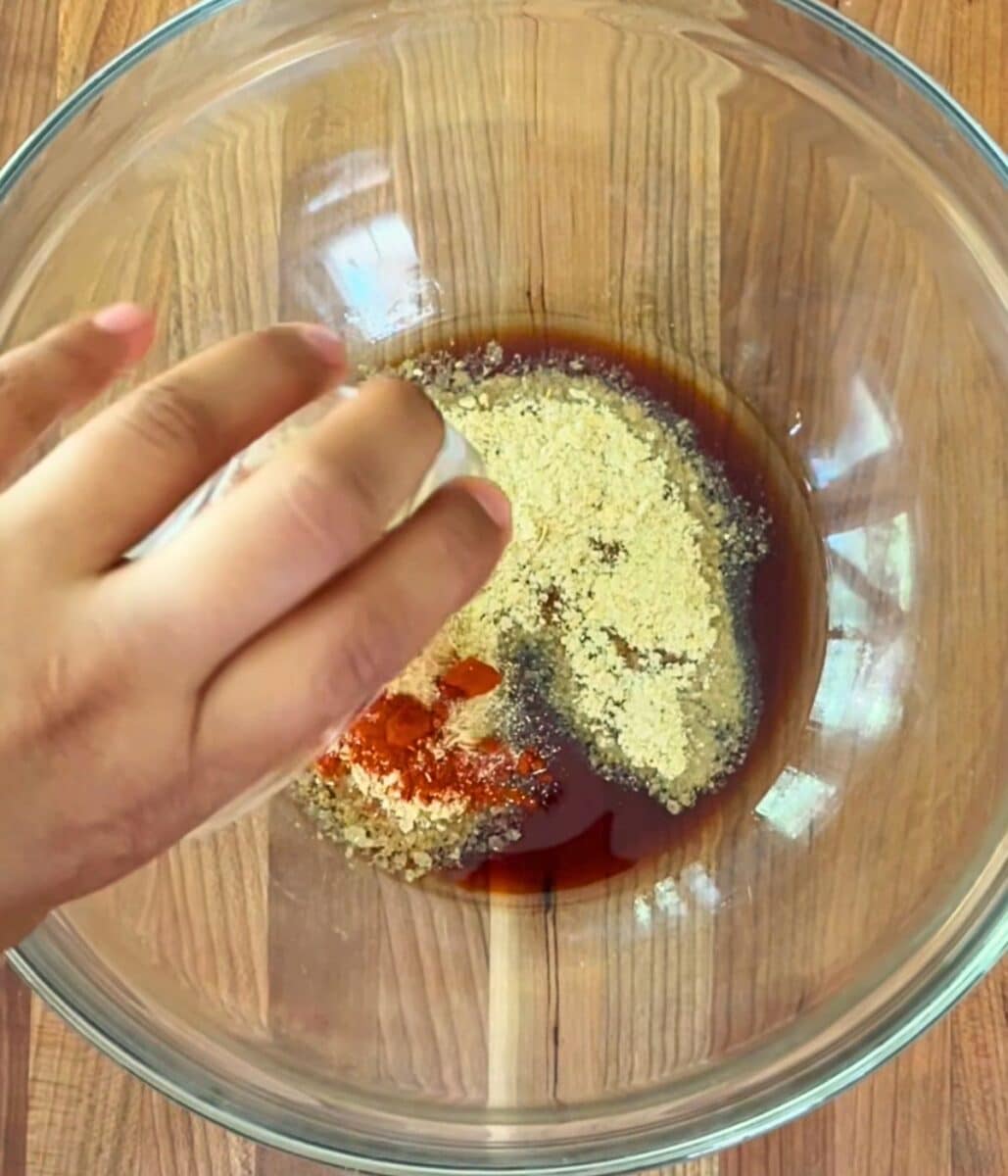 Soy sauce, nutritional yeast, paprika, and garlic powder in a glass bowl.