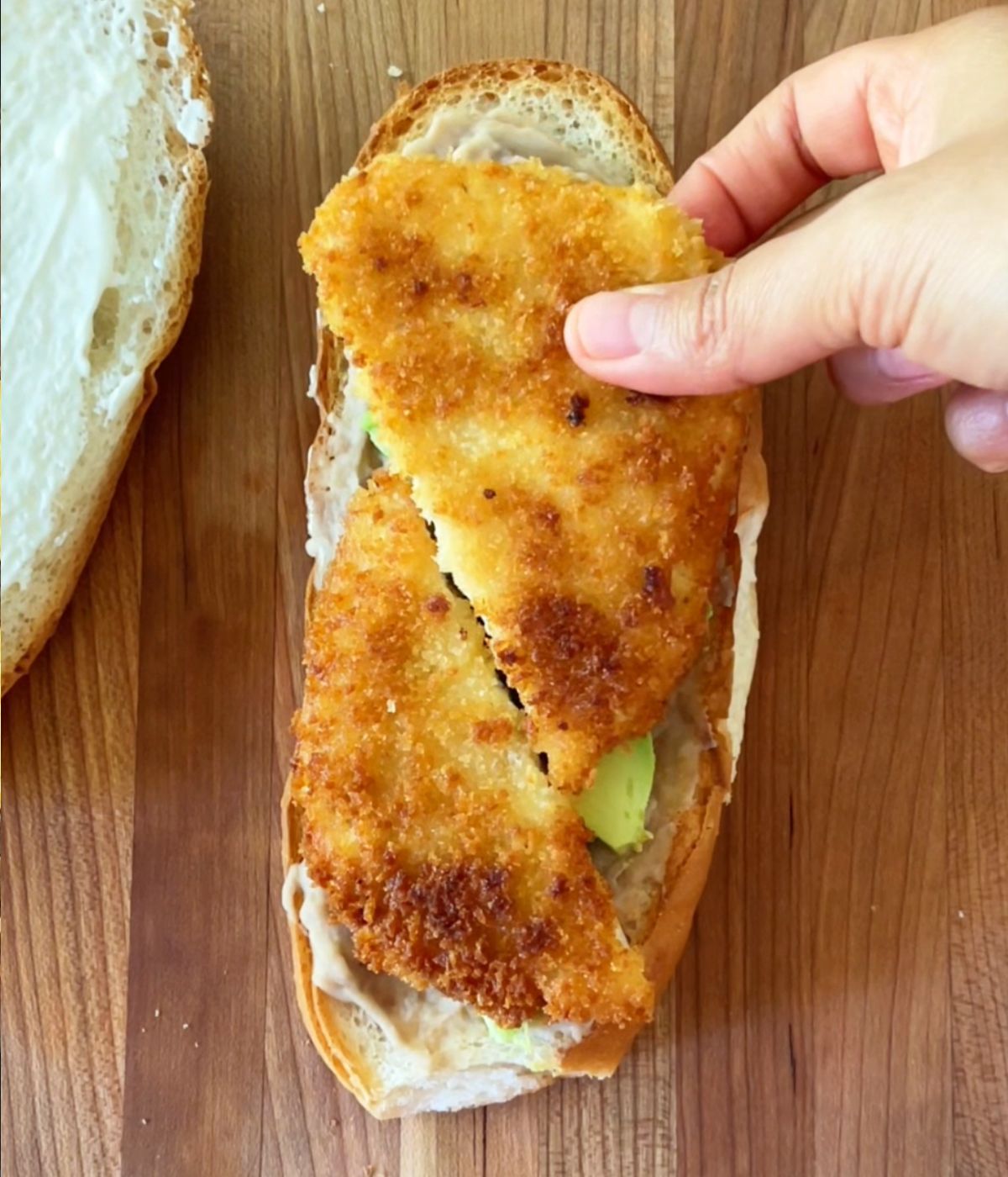 Tofu cutlet cut in half on top of torta bread.