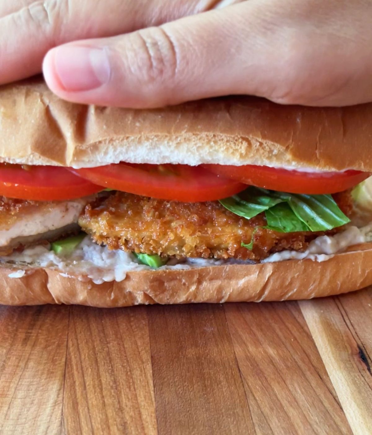 Hand pressing down on torta de milanesa.