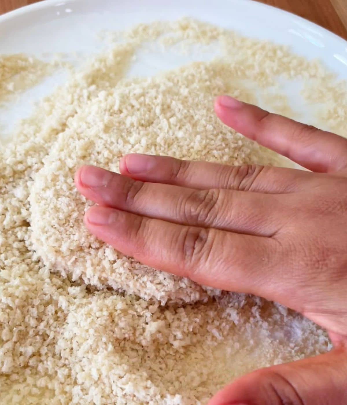 Tofu on a white plate coated with panko breadcrumbs.
