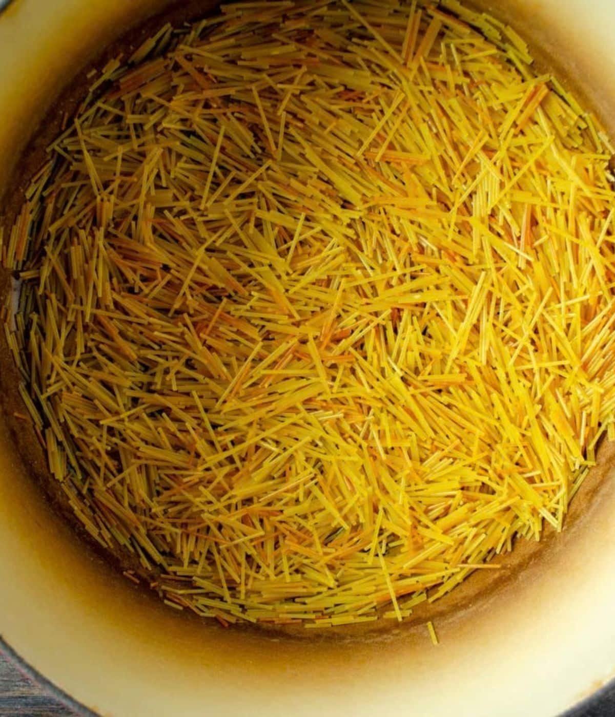 Noodles being fried in a large pot.