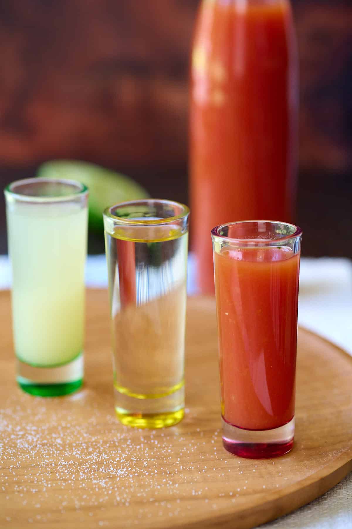 Three shot glasses, filled with sangrita, lime juice, and tequila