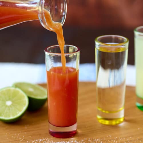 Sangrita being poured into a tall and narrow shot glass.