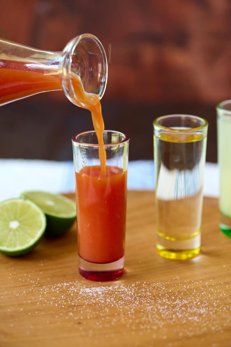 Sangrita being poured into a tall and narrow shot glass.