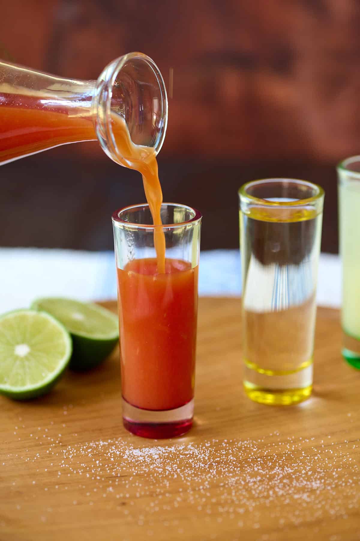 Sangrita being poured into a tall and narrow shot glass.